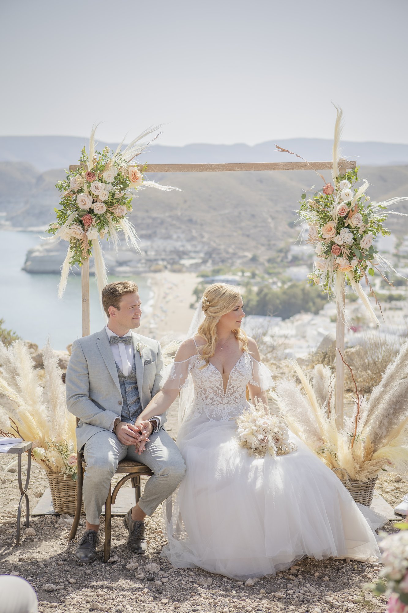 Couple sitting at the ceremony arch overlooking the bay, wedding Agua Amarga