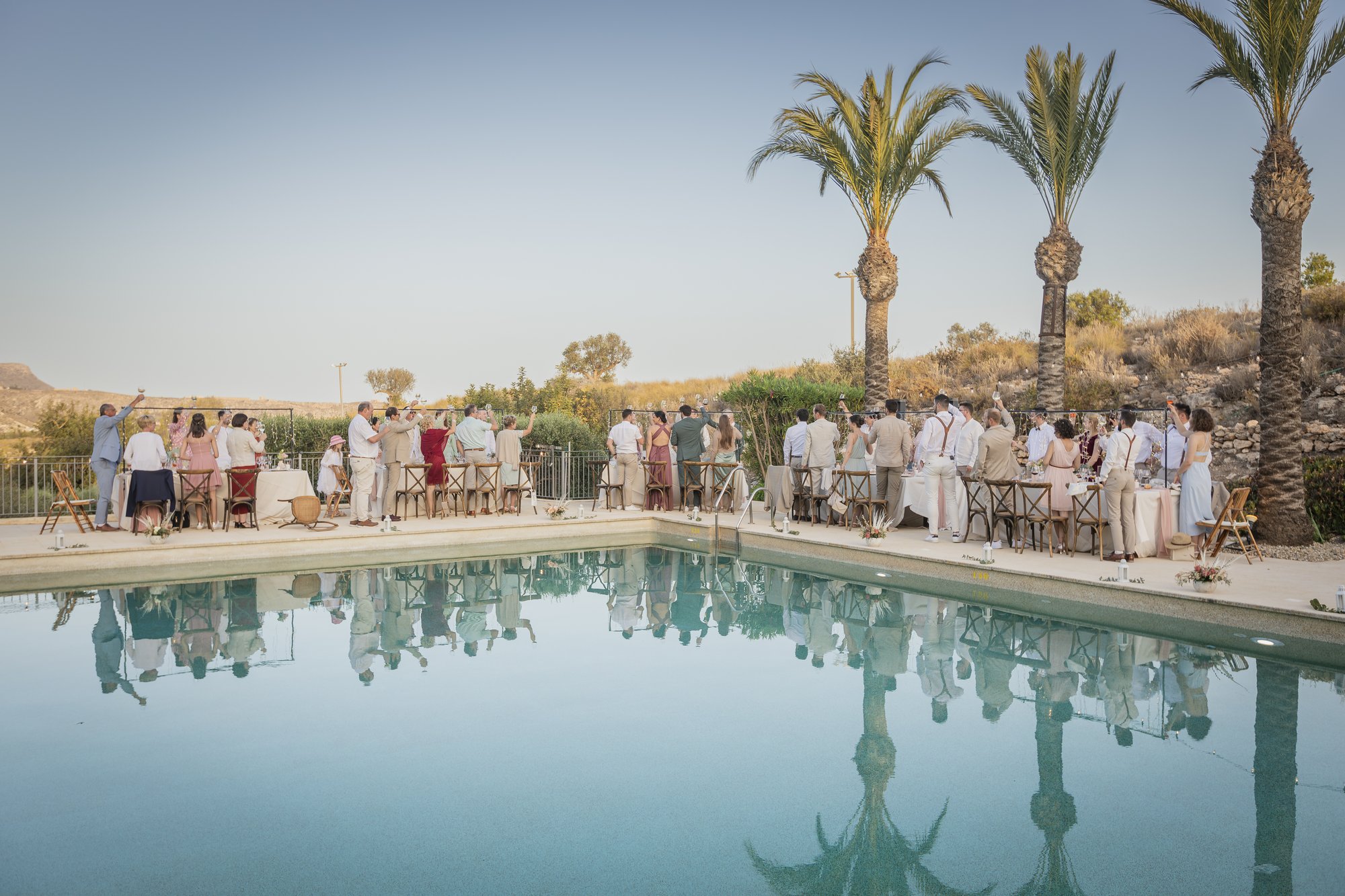 Pool with palm trees and guests in the evening light, wedding Agua Amarga